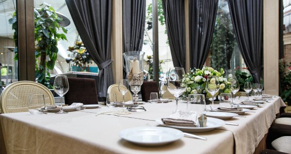 Eingedeckter Tisch im Restaurant mit stilvollen Gardinen im Hintergrund